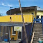 Gelbes Gebäude mit blauer Treppe und Balkon in Reparatur im Tierheim Siegen.