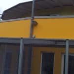 Gelbes Tierheim Siegen-Gebäude mit Netzfläche und grauem Rohr.