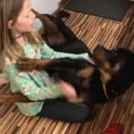 Mädchen spielt auf dem Boden und kuschelt mit einem großen schwarz-braunen Hund.