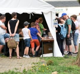 Besucher, darunter auch Kinder, versammeln sich vor einem weißen Zelt auf der Veranstaltung im Tierheim Siegen.