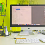 Schreibtisch mit Computer, Tastatur, Telefon und Büromaterial.