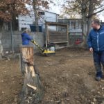 Eine Person benutzt eine gelbe Müllpresse, während eine andere in der Nähe zusieht.