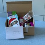 Kiste mit Tiergeschenken und Karte vom Tierheim Siegen auf blauem Boden.