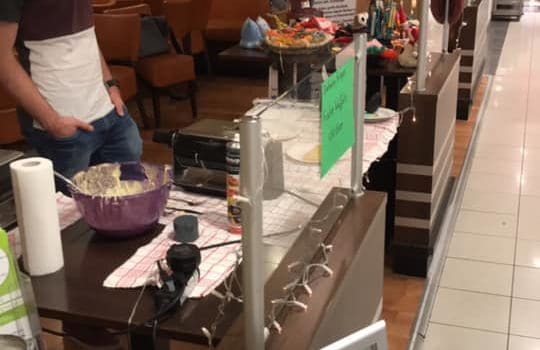 Mann am Tierheim Siegen Tisch mit Essen, Adoptionsschild im Einkaufszentrum.