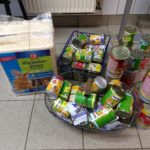 Tierfutterdosen und Tierstreu auf dem Boden neben zwei Körben.