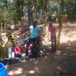 Kinder an einem Teich im Wald, die Schilfhalme festhalten und das Wasser betrachten.