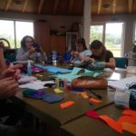 Fünf Mädchen basteln an einem Tisch mit Filz und Papier in einem hellen Raum.