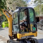 Person mit einem gelben JCB-Bagger in der Nähe des Tierheims Siegen.