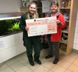 Zwei Frauen im Tierheim Siegen halten einen großen Spendenscheck in der Hand.