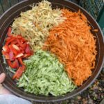 Teller mit geschreddertem Gemüse, der draußen in der Nähe eines Zauns steht.