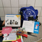 Tisch mit Tierbedarf, Broschüren, Leckerlis und blauer Hundetasche des Tierheims Siegen.