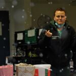 Verwirrte Frau in der Küche, Maske unter dem Kinn, Essensbehälter in der Nähe.