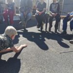 Ein Kind krabbelt auf Gegenstände zu, während andere von einer Bank aus zusehen.