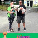 Lächelndes Paar mit zwei weißen Hunden im Tierheim Siegen, Danke-Schild.