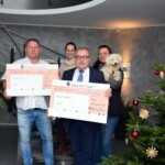 Foto: Jürgen Schade, Siegen Vier Personen mit großen Schecks und einem Hund an einem Weihnachtsbaum im Tierheim Siegen.