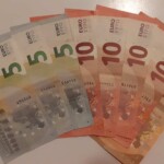 Euro-Banknoten (5er, 10er, 50er) aufgefächert auf weißer Fläche.