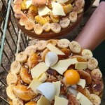 Zwei Platten mit Bananen, Eiern und Käse werden von einer Person in der Nähe eines Zauns gehalten.