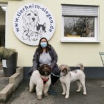 Maskierte Frau mit zwei Hunden vor dem Tierheim Siegen.