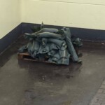 Zusammengeklappte künstliche Weihnachtsbäume, die auf einer Palette vor einer gelben Wand gestapelt sind.