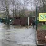 Jemand sprüht Wasser auf den nassen Bürgersteig bei den Tiergehegen.