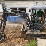 Ein Mann benutzt einen kleinen Volvo-Bagger in der Nähe des Tierheims Siegen.
