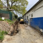 Ein Bagger gräbt neben dem blau-weißen Gebäude des Tierheims Siegen.