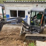 Ein Mann benutzt einen Volvo-Bagger in der Nähe des Gebäudes des Tierheims Siegen.