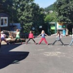Fünf Kinder strecken Arme und Beine in der Sonne aus.